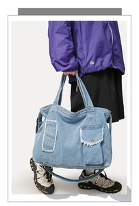 Détail du sac cabas en denim bleu clair avec bords effilochés et bandoulière réglable