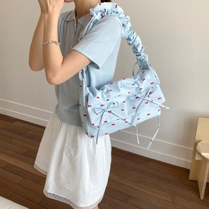 Light blue pleated shoulder bag with red bow print and ruffle strap shown on model