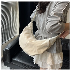 Detail view of cream corduroy dumpling bag worn as a stylish minimalist crossbody purse