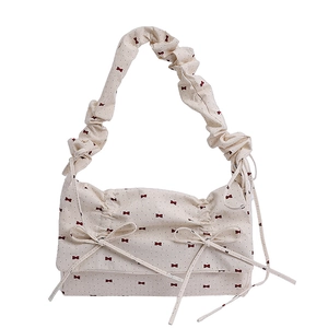 Floral shoulder bag with cream fabric, red bows, and pleated strap in a French retro style