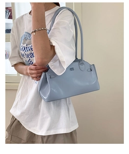 Détail d'un sac à bandoulière bleu clair brillant avec logo gaufré et anses élégantes