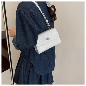 Close-up of white croc-embossed shoulder bag featuring a silver metal twist lock buckle