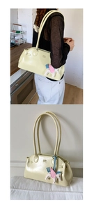 Détail du sac à bandoulière jaune crème en cuir brillant avec breloque cheval
