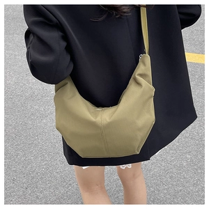 Close-up of olive green crescent crossbody bag with textured fabric and adjustable strap