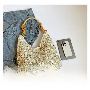 Crochet tote bag with wooden bead handle next to a tablet and denim jacket for size comparison