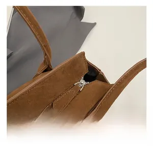 Close-up of premium silver metal zipper and brown suede texture on a tote bag