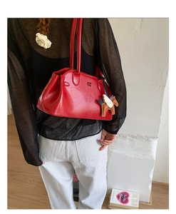 Détail d'un sac à bandoulière en cuir rouge avec un charm cheval et fini brillant