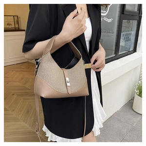 Détail du sac bi-matière tissé avec fermoir rotatif en métal et bandoulière réglable
