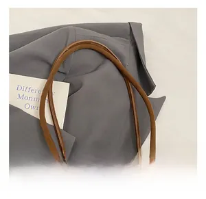 Detail shot of slim cylindrical shoulder strap on a brown suede tote bag