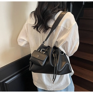 Detail of black pleated bucket bag featuring drawstring closure and mini charm pendant