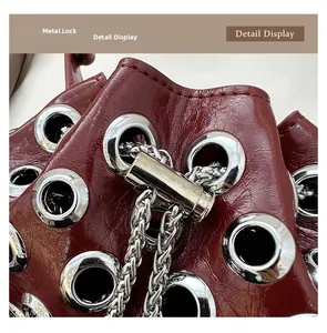 Macro detail of wine red bucket bag with glossy leather texture and silver metal grommets