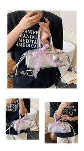 Détail du sac Boston argenté avec ruban en dentelle rose et pendentif nœud élégant