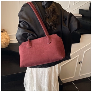 Detail of burgundy suede tote bag with long straps worn by a model in a retro setting