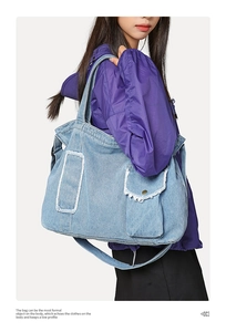 Détail du grand sac cabas en jean bleu clair avec bords effilochés et poche avant