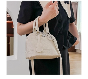Schicke beige Damen-Muscheltasche, von einem Model in hellem Innenraum-Ambiente präsentiert