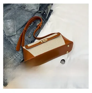 Detailed view of the brown leather and beige canvas handbag with gold twist-lock closure