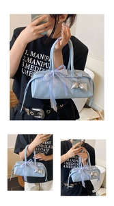 Détail du sac en cuir verni bleu clair avec nœud en dentelle et pendentif argenté