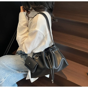 Detail of minimalist black drawstring bucket bag with silver hardware and mini pouch