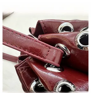 Macro shot of silver metal grommet eyelets and stitching on dark red waxed leather bag