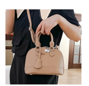 Detail der hellbraunen Shell-Tasche mit Lychee-Maserung und eleganter Form