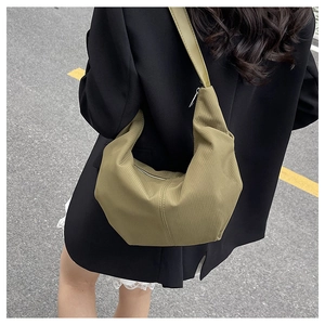 Outdoor shot of an olive green corduroy crescent bag showing texture and shoulder strap