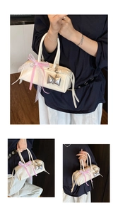 Détail du sac à main en cuir verni blanc avec rubans en dentelle et breloques de nœuds