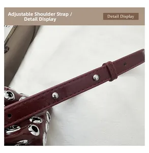 Detail display of the punk-style adjustable rivet strap on burgundy leather bucket bag