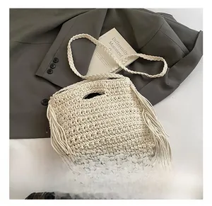 Macro shot of off-white hand-knitted texture and decorative side fringe on a small square bag