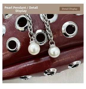 Macro detail of wine red wrinkled leather bag with silver eyelets and white pearl charms