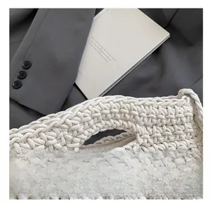 Detailed close-up of handmade knit handle on a cream woven crossbody bag with soft textures
