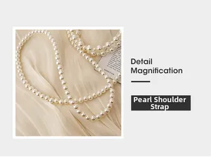 Détail d'une bandoulière en perles blanches lustrées sur un tissu en soie douce