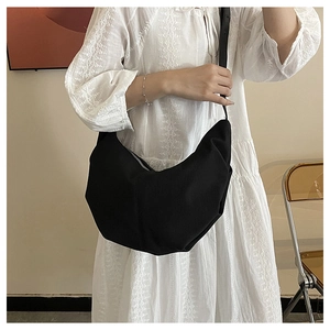 Detail view of large black canvas hobo bag worn by model in minimalist studio