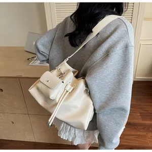 Detail of cream-colored pleated bucket bag with mini pouch and drawstring closure