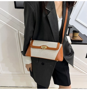 Detail of white canvas crossbody bag with brown leather trim and golden lock buckle