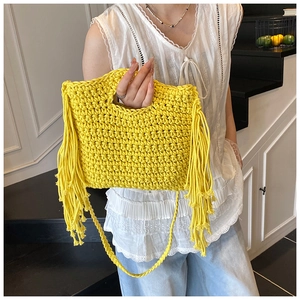 Detailed view of bright yellow hand-woven knit bag featuring thick decorative tassels