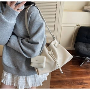 Detail view of cream shoulder tote bag with drawstring closure and small matching pouch