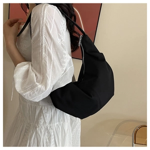 Close-up of minimalist black nylon crescent bag worn by model showing sleek texture and style