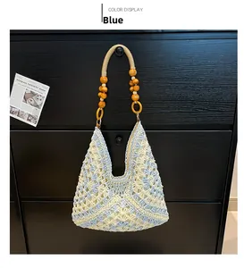 Detail of blue and white crochet tote bag with decorative orange wooden beads