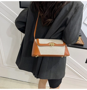 Detail of a contrast color canvas shoulder bag with gold ring lock and protective feet
