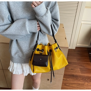 Detailed shot of yellow textured leather bucket bag with a mini brown pouch accessory