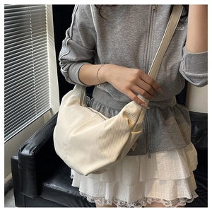 Detail of cream pleated crescent bag showing soft PU leather texture and vertical folds