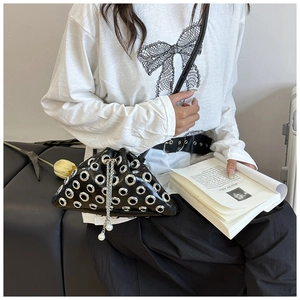 Close-up of black rivet bucket bag with silver metal eyelets and pearl charm detail