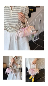 Détail du sac boston en cuir verni rose avec nœud, dentelle et breloque argentée