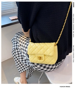 Detail van gele gewatteerde crossbodytas met gouden ketting gedragen door model