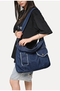 Détail du sac cabas en jean bleu foncé avec bords effilochés et design multi-poches