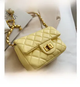 Detail van gele gewatteerde crossbodytas met gouden ketting en metalen draaisluiting