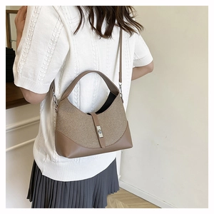 Detail of two-tone beige and brown shoulder bag with silver metal buckle on a model