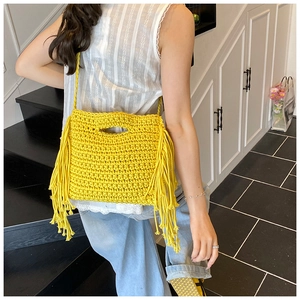 Close-up of vibrant yellow hand-knitted crossbody bag with bohemian tassel fringe detail
