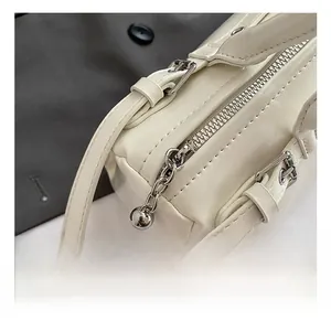 Détails du sac bandoulière crème avec fermeture éclair sphérique argentée et coutures fines