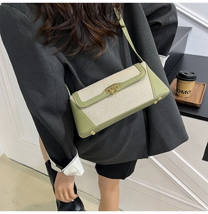Close-up of contrast crossbody bag featuring green leather and beige canvas details